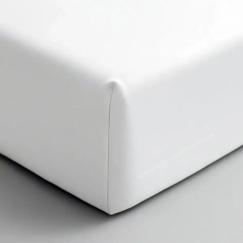 White fitted sheet corner on mattress showing elastic edge and smooth percale fabric - Linen & Co hospitality bedding