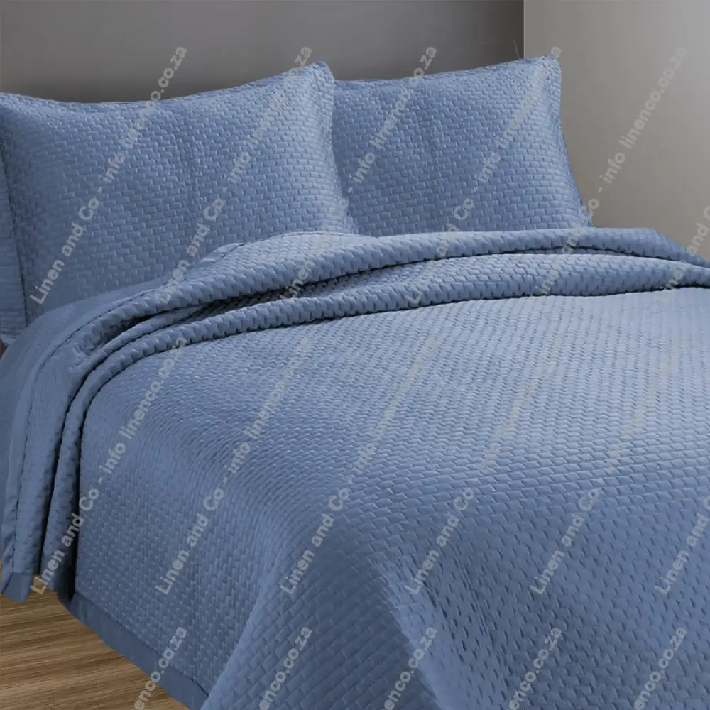French Blue Berlin design quilted bedspread with matching pillow cases on a bed.