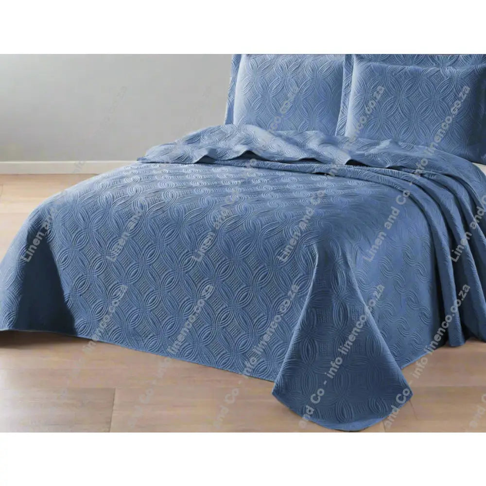 French Blue Munich Design quilted bedspread on a bed with matching pillows.