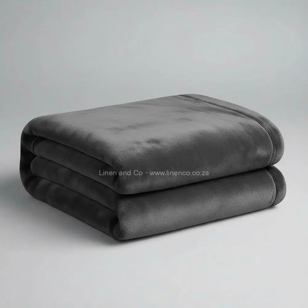 Grey luxury plush blanket neatly folded on light grey background - Linen and Co premium microfibre hospitality blanket