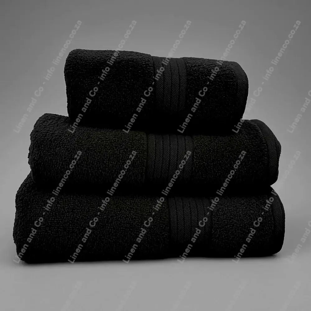 Linen and Co - Stack of three Black Egyptian 450gsm towels stacked on a grey background.