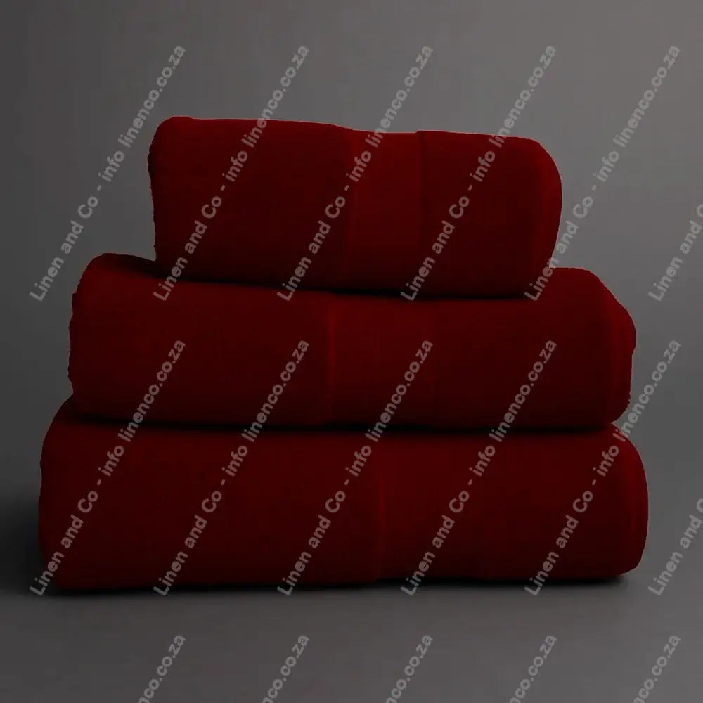 Linen and Co - Stack of three Burgundy Egyptian 450gsm towels stacked on a grey background.