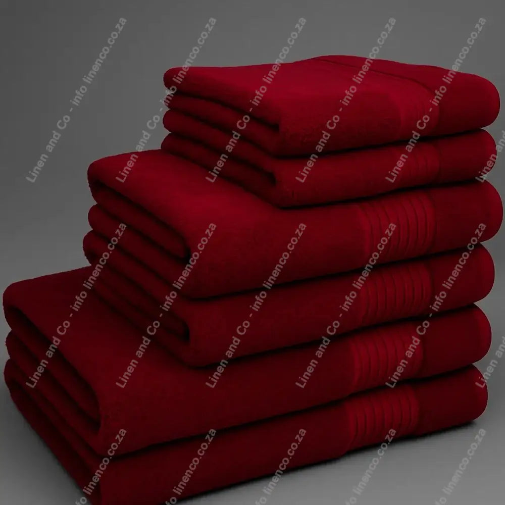 Linen and Co - Big and Soft Stack of burgundy towels on a grey background