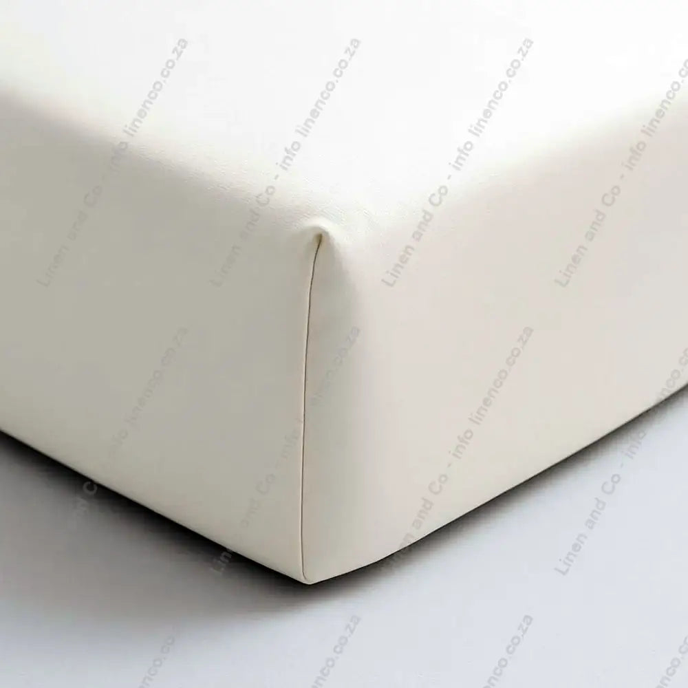 Close-up of a beige fitted sheet on a bed corner.