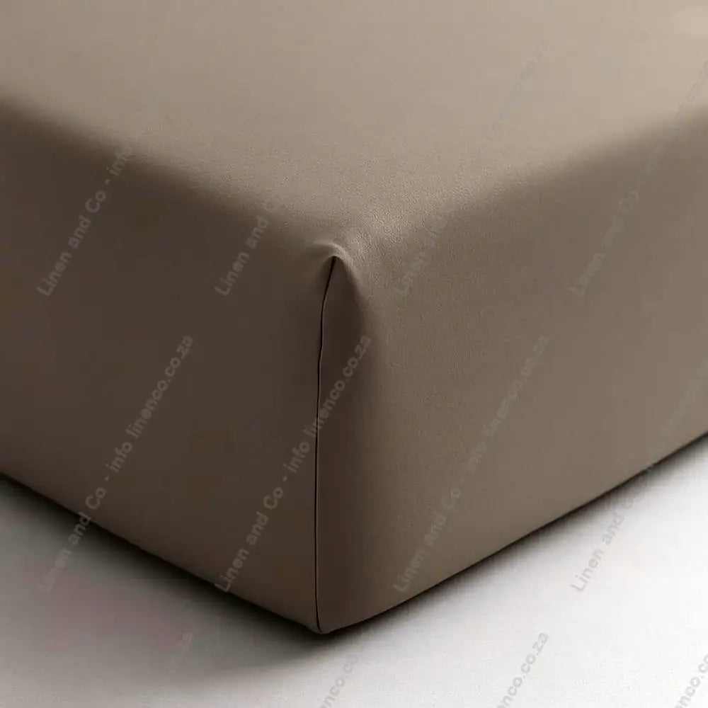 stone fitted sheet on a bed corner with a plain background