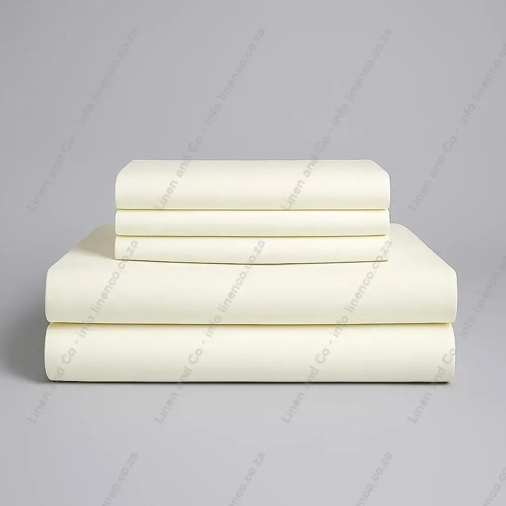 Set of cream folded bed sheets on a grey background
