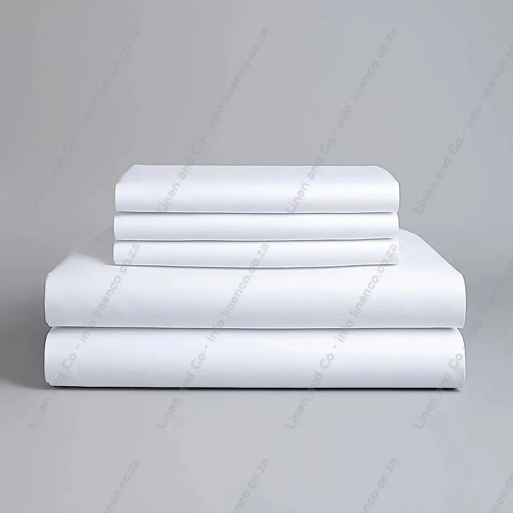 Set of white folded bed sheets on a grey background
