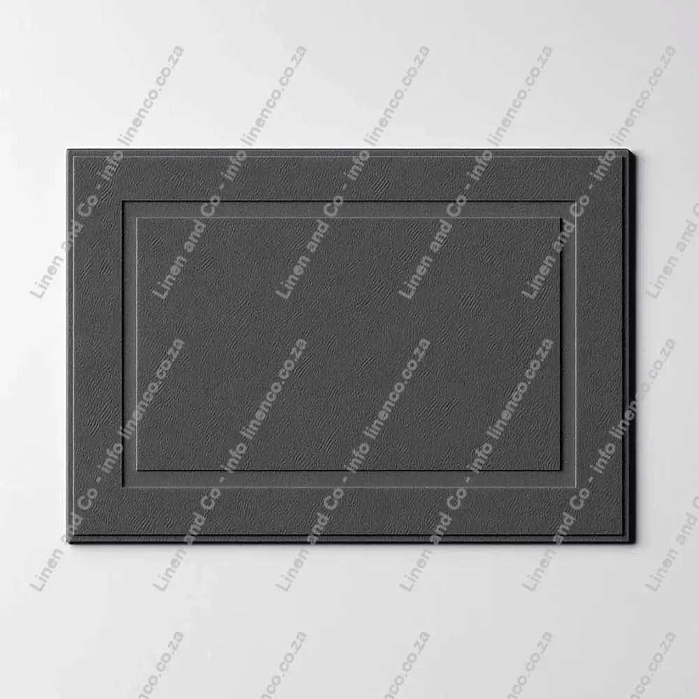 Grey rectangular towelling bath mat on a grey background