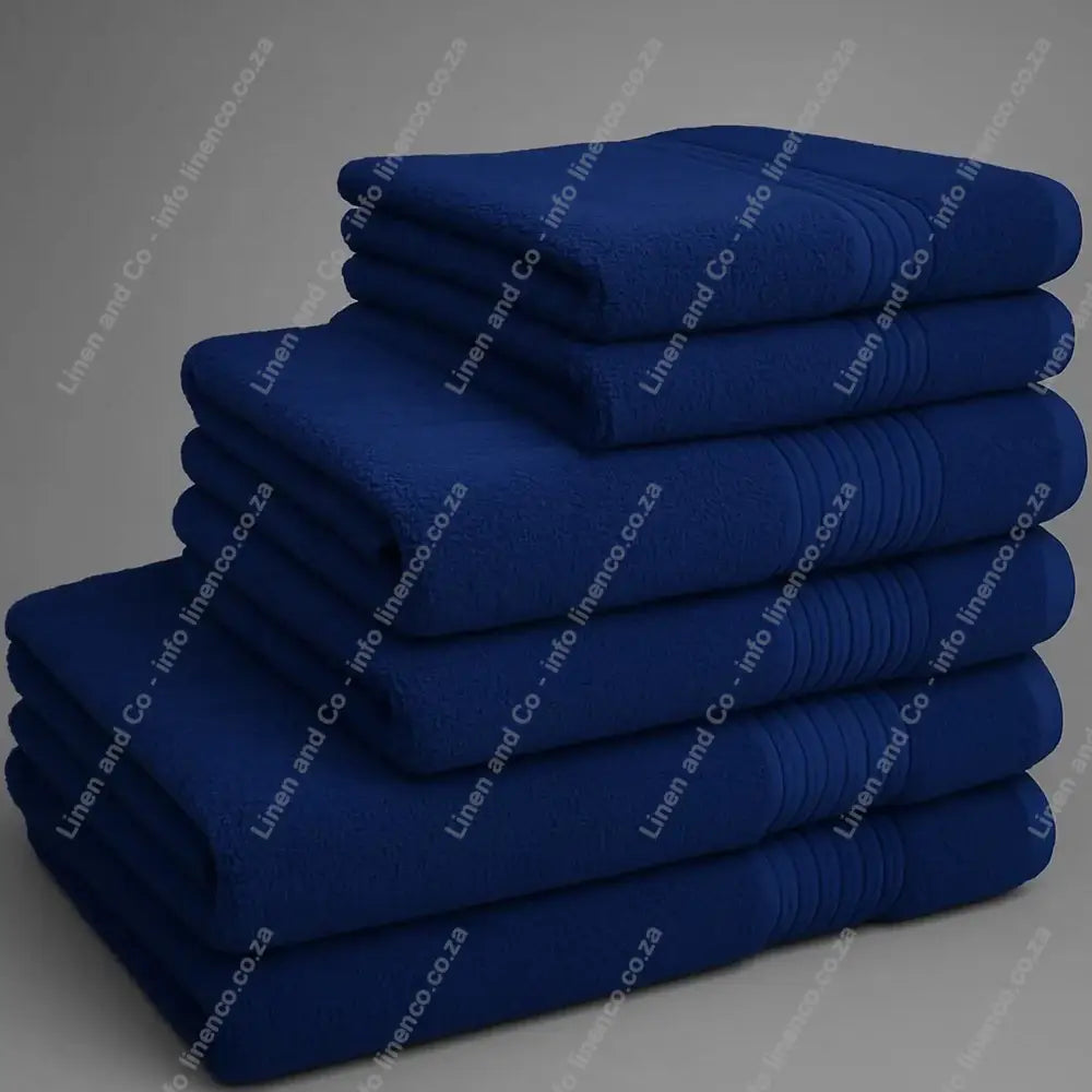 Linen and Co - Big and Soft Stack of navy blue towels on a grey background