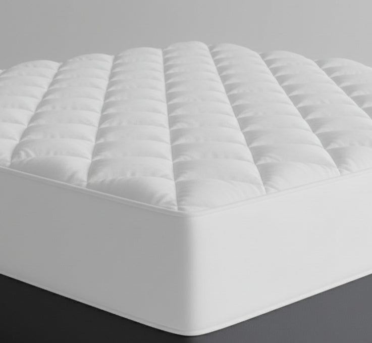 White quilted mattress protector with detailed diamond pattern on top, plain white sides, showcasing premium hospitality-grade protection.