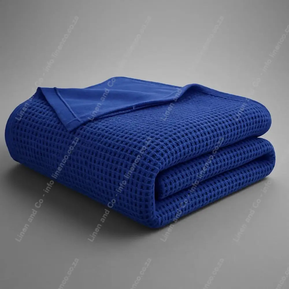 Linen and Co Royal Blue Cotton Cellular blanket folded on a grey background