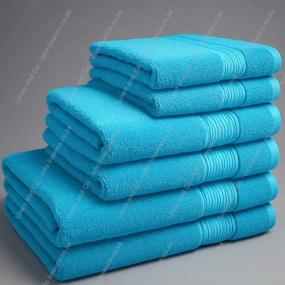 Linen and Co - Big and Soft Stack of teal towels on a grey background