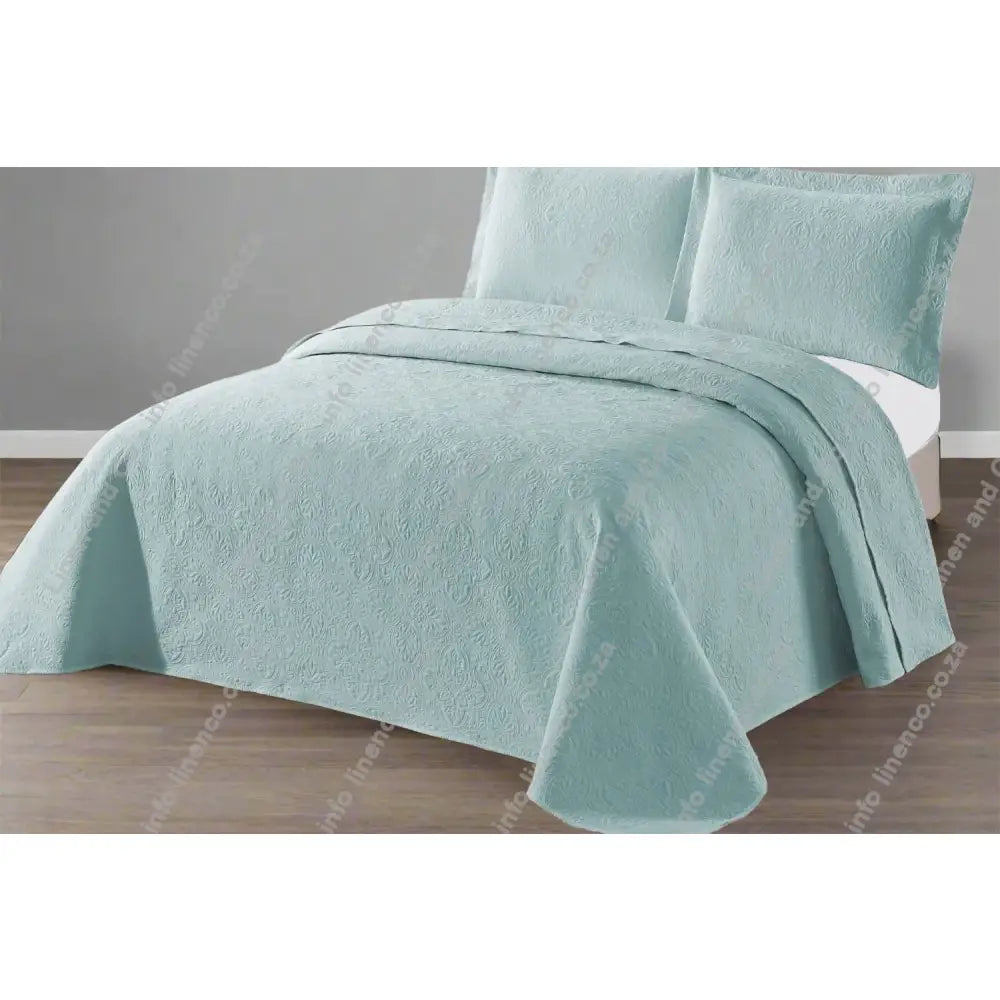 Marine Daisy Design Quilted bedspread on a bed with a grey wall background