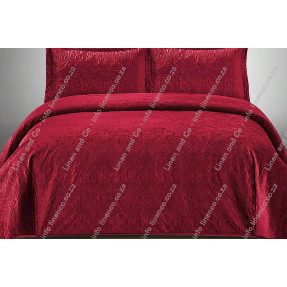 Maroon French velvet quilted bedding set on a bed with matching pillows