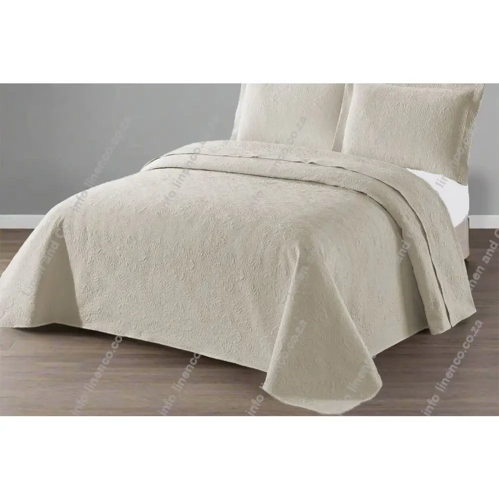Natural Daisy Design Quilted bedspread on a bed with a grey wall background