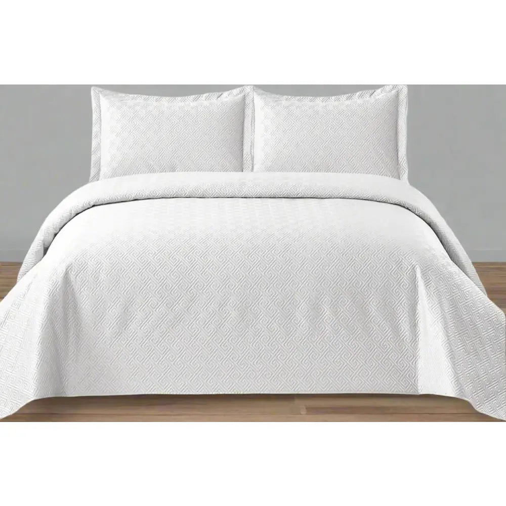 White Rome Design Quilted Bedspread set on a bed.