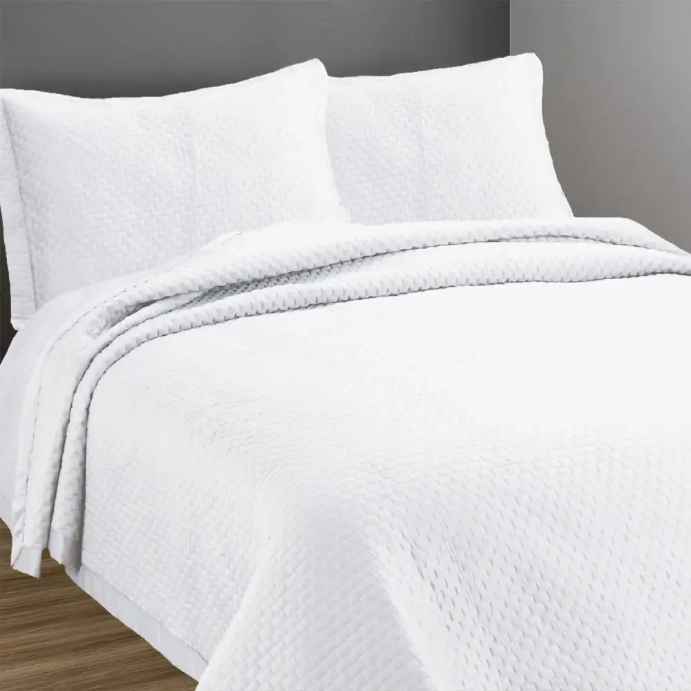 White Berlin design quilted bedspread with matching pillow cases on a bed.