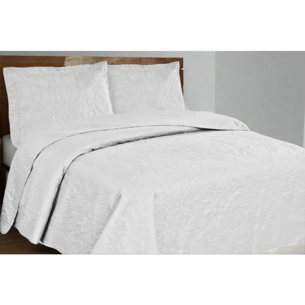 White Melissa Design textured quilt and pillow set on a bed in a bedroom setting.