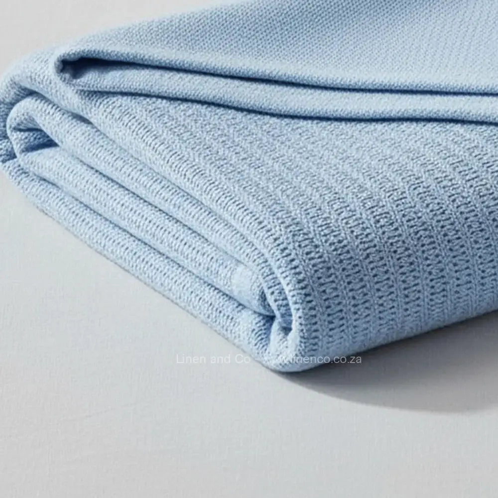 blue cotton cellular blanket showing textured waffle weave fabric on neutral grey background—soft, breathable bedding by Linen & Co