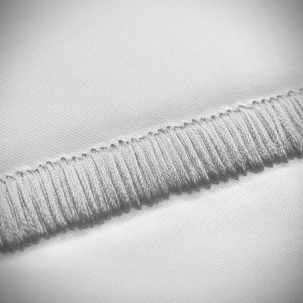 Close-up of grey satin stitch detail on white percale by Linen and Co 