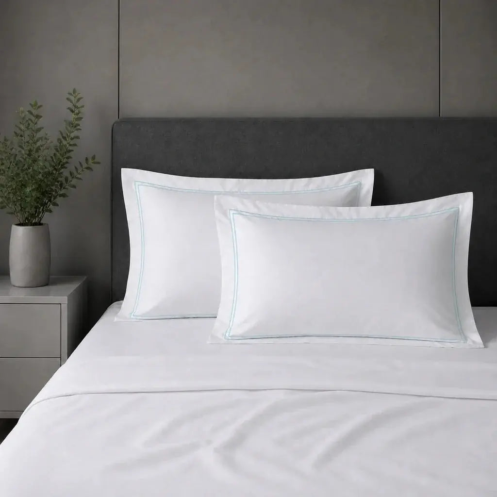White 100% cotton percale 200TC Oxford pillow cases on a bed with Duck Egg two-row satin stitch.