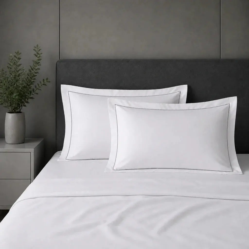 White 100% cotton percale 200TC Oxford pillow cases on a bed with Grey one-row satin stitch.