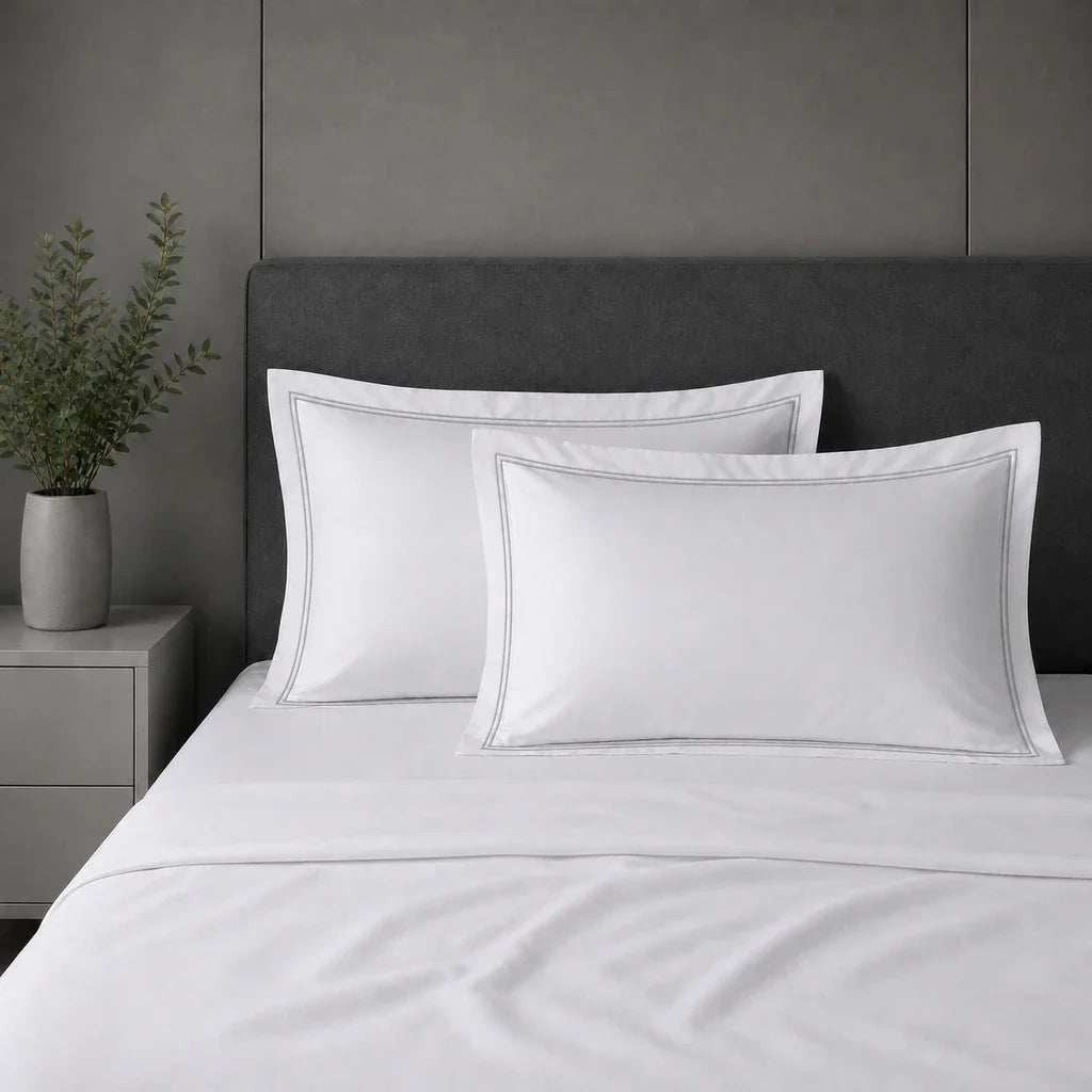 White 100% cotton percale 300TC Oxford pillow cases on a bed with Grey two-row satin stitch.