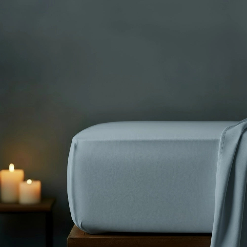 Duck egg fitted sheet on bed with candlelight ambiance against moody dark grey wall—premium cotton percale fitted sheet by Linen & Co