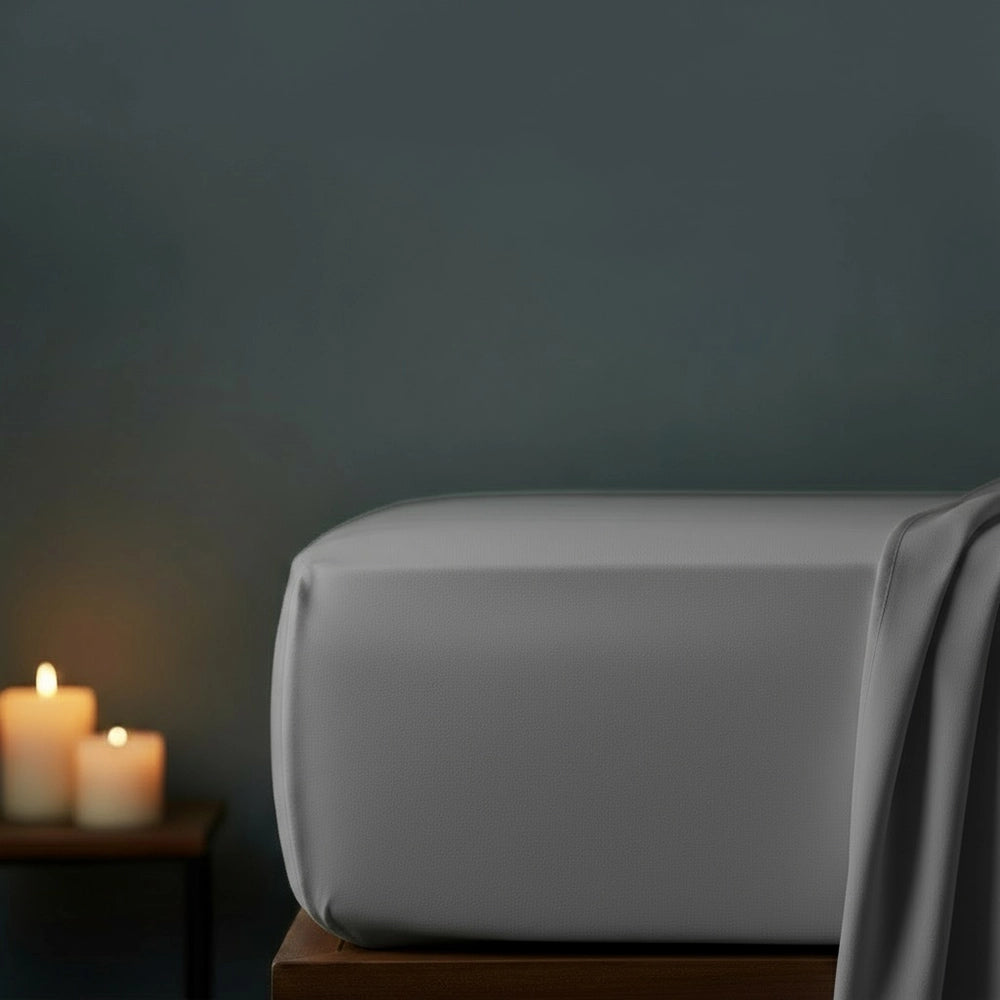 Grey fitted sheet on bed with candlelight ambiance against moody dark grey wall—premium cotton percale fitted sheet by Linen & Co
