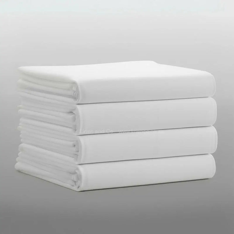 Stack of folded white percale 200TC flat sheets on light grey background—durable, colour-fast flat sheets by Linen & C