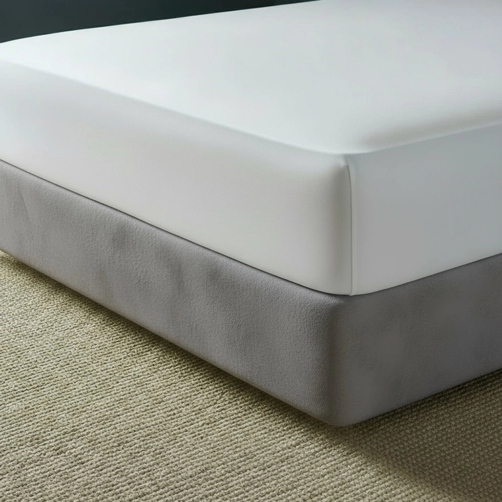 Grey mock suede base wrap covering bed base with white fitted sheet on beige jute mat—luxury bed base cover by Linen & Co