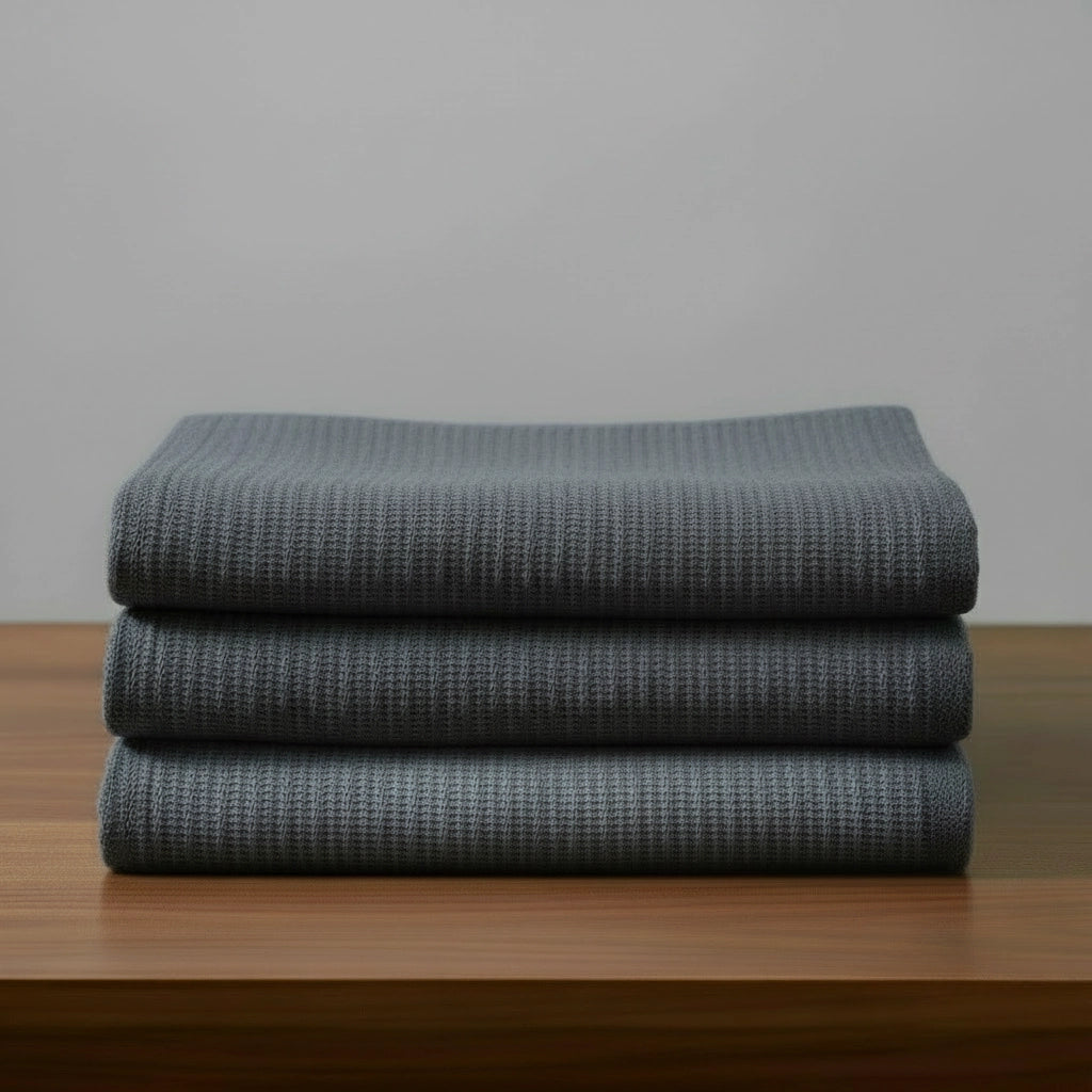 Grey cotton cellular blanket by Linen and Co, neatly folded to showcase breathable cellular knit texture for hospitality and home.