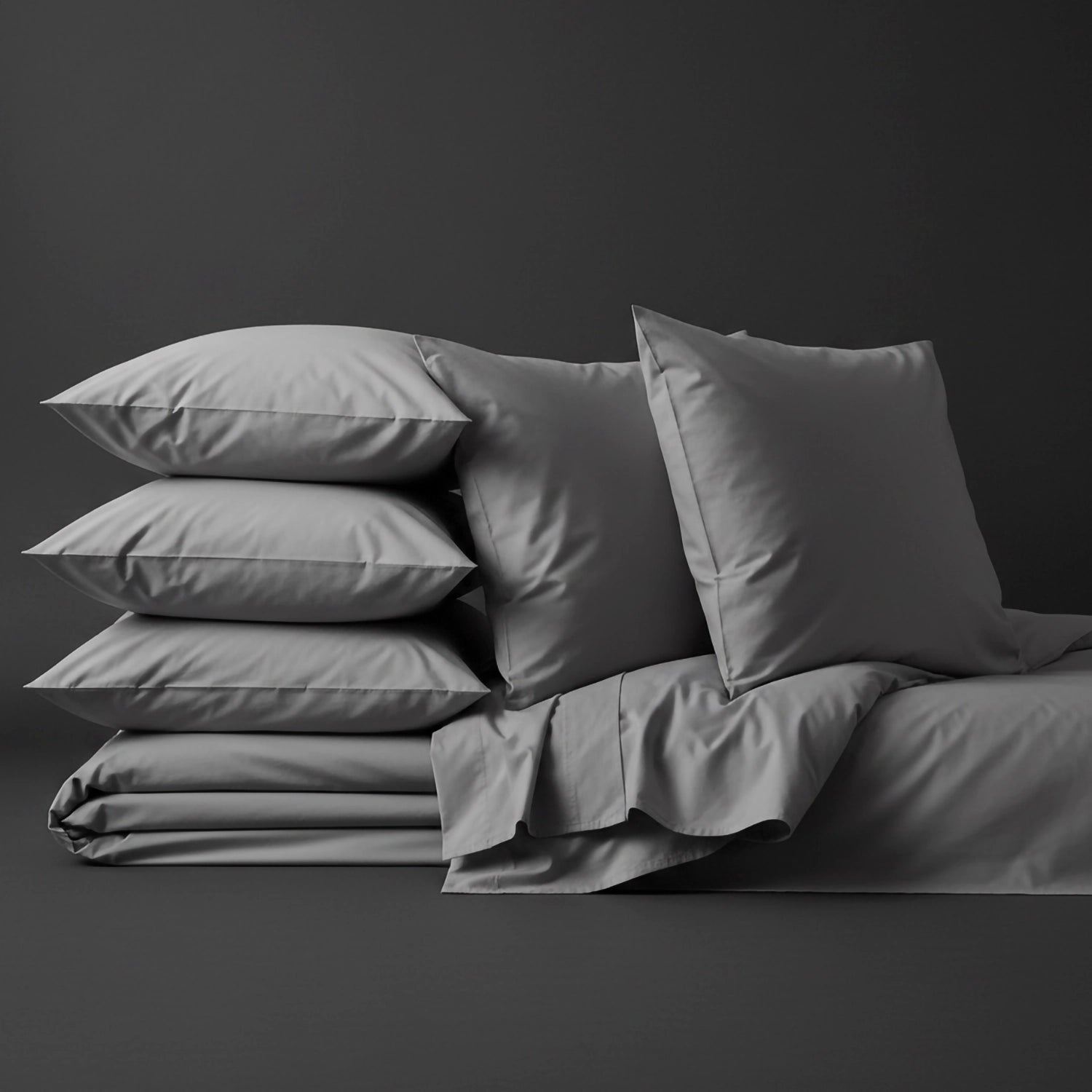 Grey percale bed linen and pillowcases by Linen and Co, stacked to showcase crisp, premium bedding for hospitality and home.