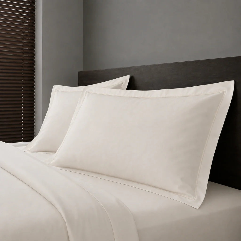Ivory Cream Polycotton Percale 200TC Oxford pillow cases on a bed with Cream one-row satin stitch - Linen and Co