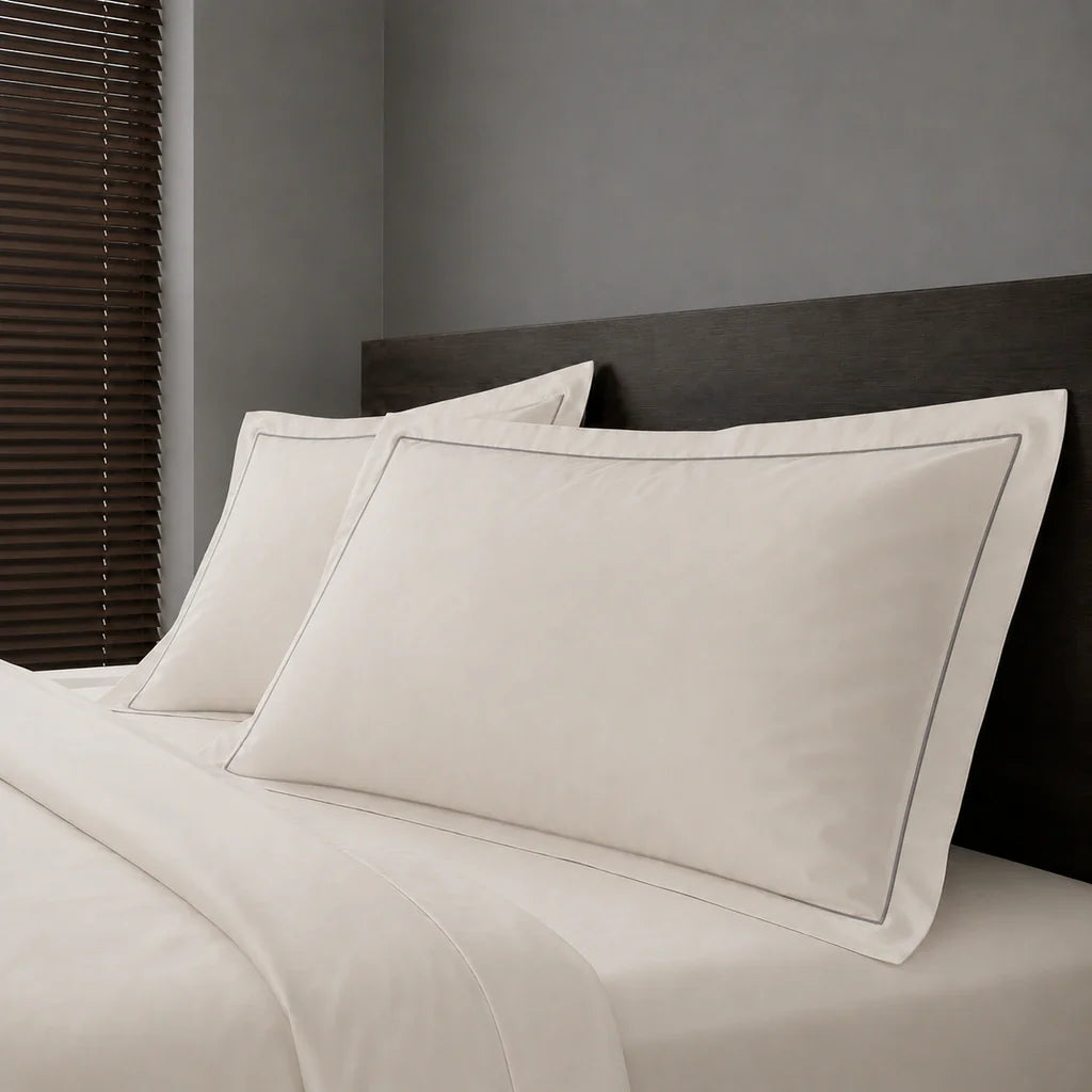Ivory Cream Polycotton Percale 200TC Oxford pillow cases on a bed with Grey one-row satin stitch - Linen and Co
