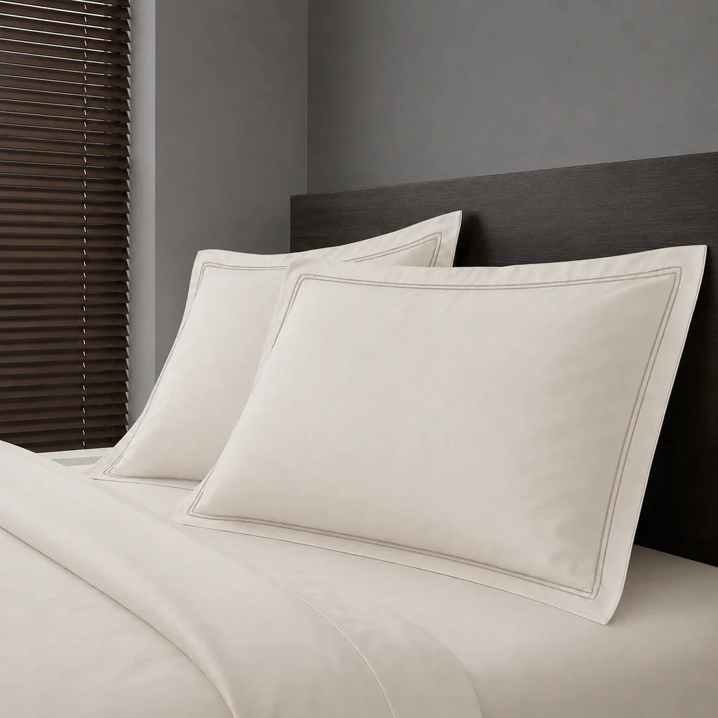 Ivory Cream Polycotton Percale 200TC Oxford pillow cases on a bed with Stone two-row satin stitch - Linen and Co