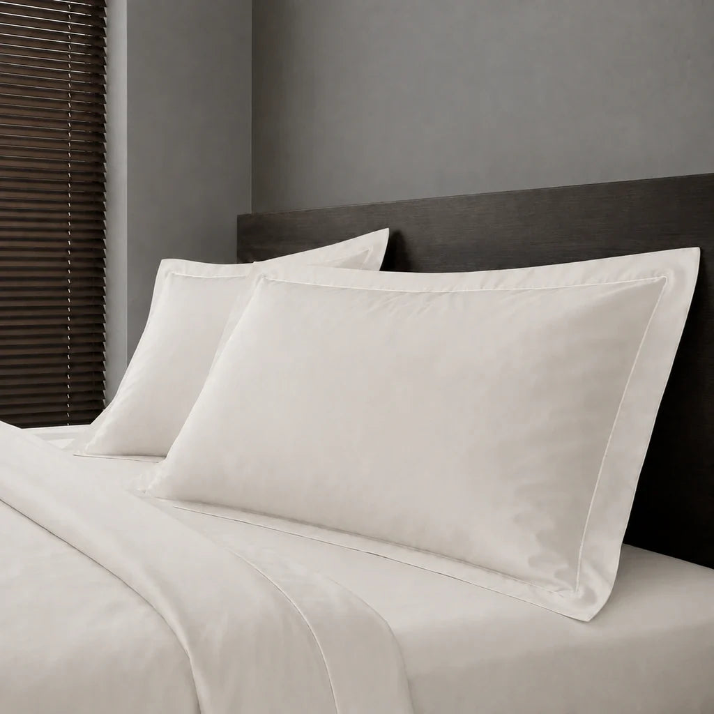 Ivory Cream Polycotton Percale 200TC Oxford pillow cases on a bed with White one-row satin stitch - Linen and Co
