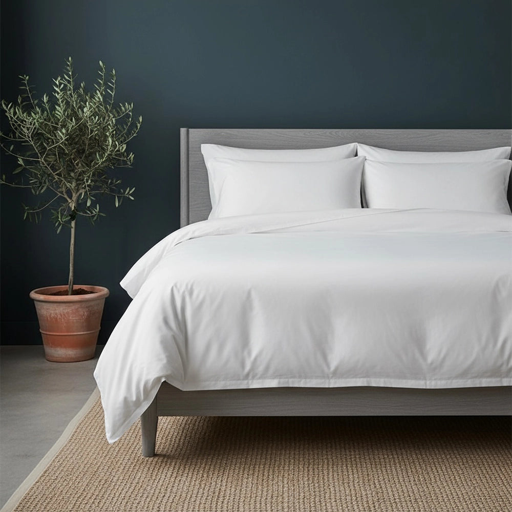 Linen & Co white cotton percale duvet cover and pillowcases in minimalist luxury bedroom setting with moody dark wall, wooden furniture, and botanical styling