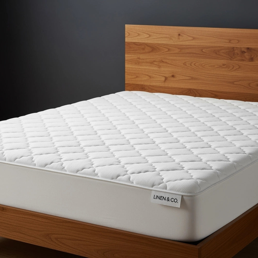 Linen & Co quilted wetsafe mattress protector with waterproof polyurethane barrier, displayed on wooden bed frame.
