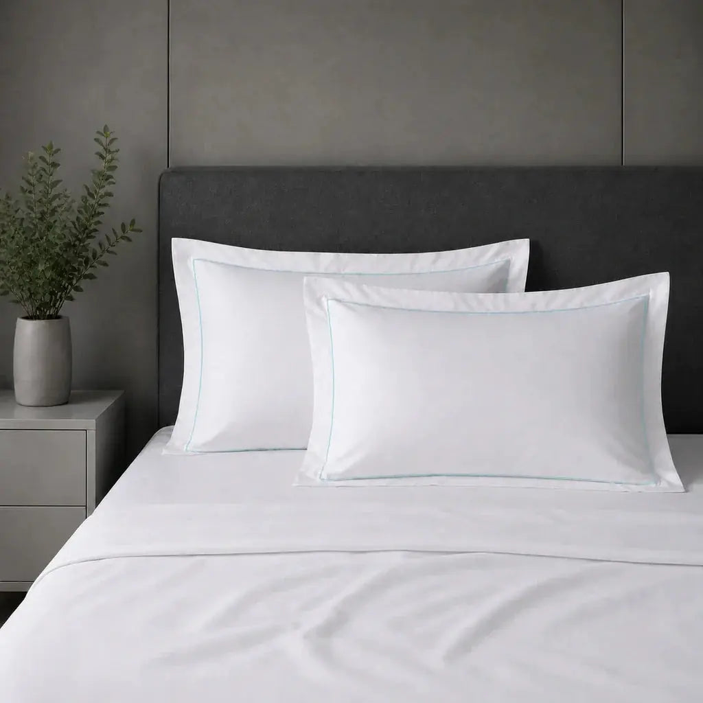 White polycotton percale 200TC Oxford pillow cases on a bed with Duck Egg one-row satin stitch.