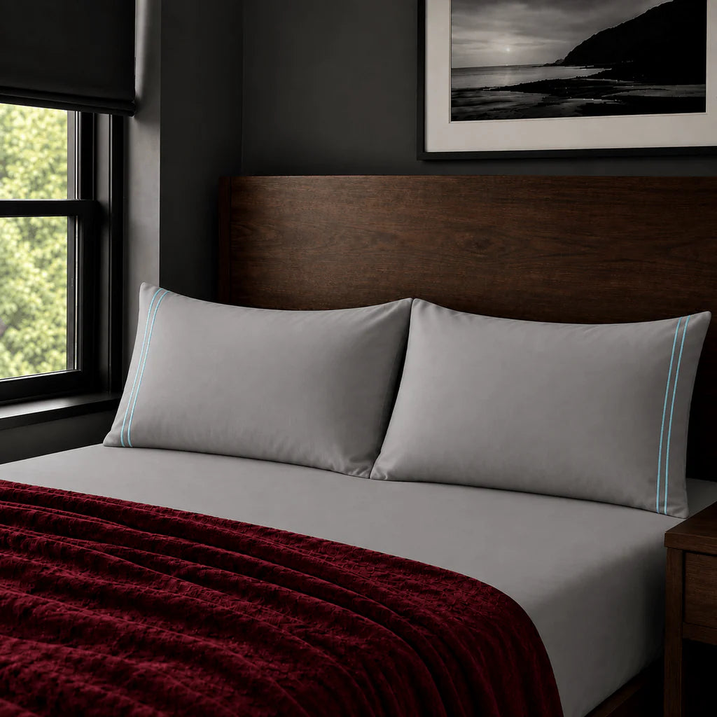 Plain grey 200TC polycotton percale pillowcases with two row duck egg satin stitch border by Linen and Co