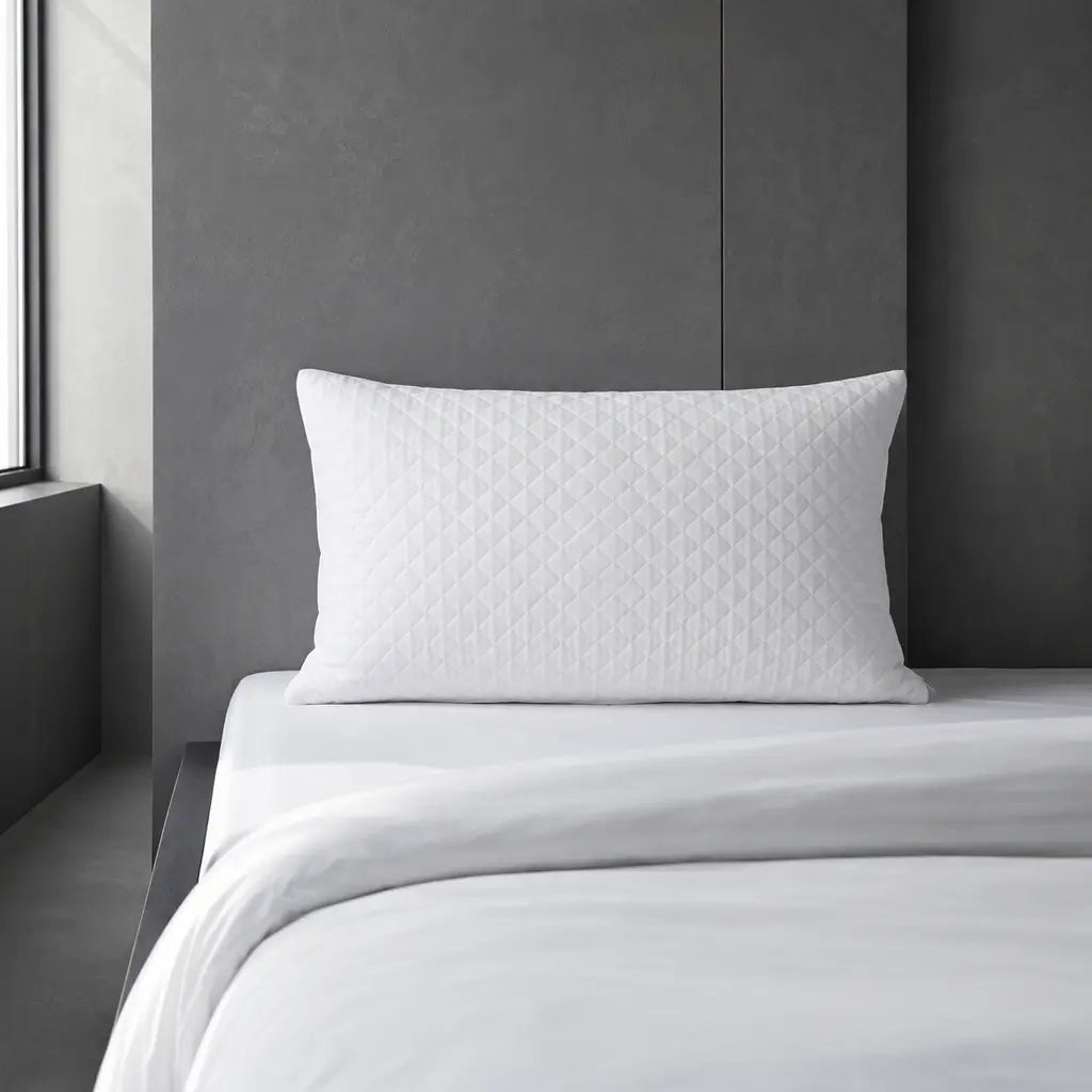 Quilted Wetsafe pillow protector on a cool grey hotel bed by Linen and Co