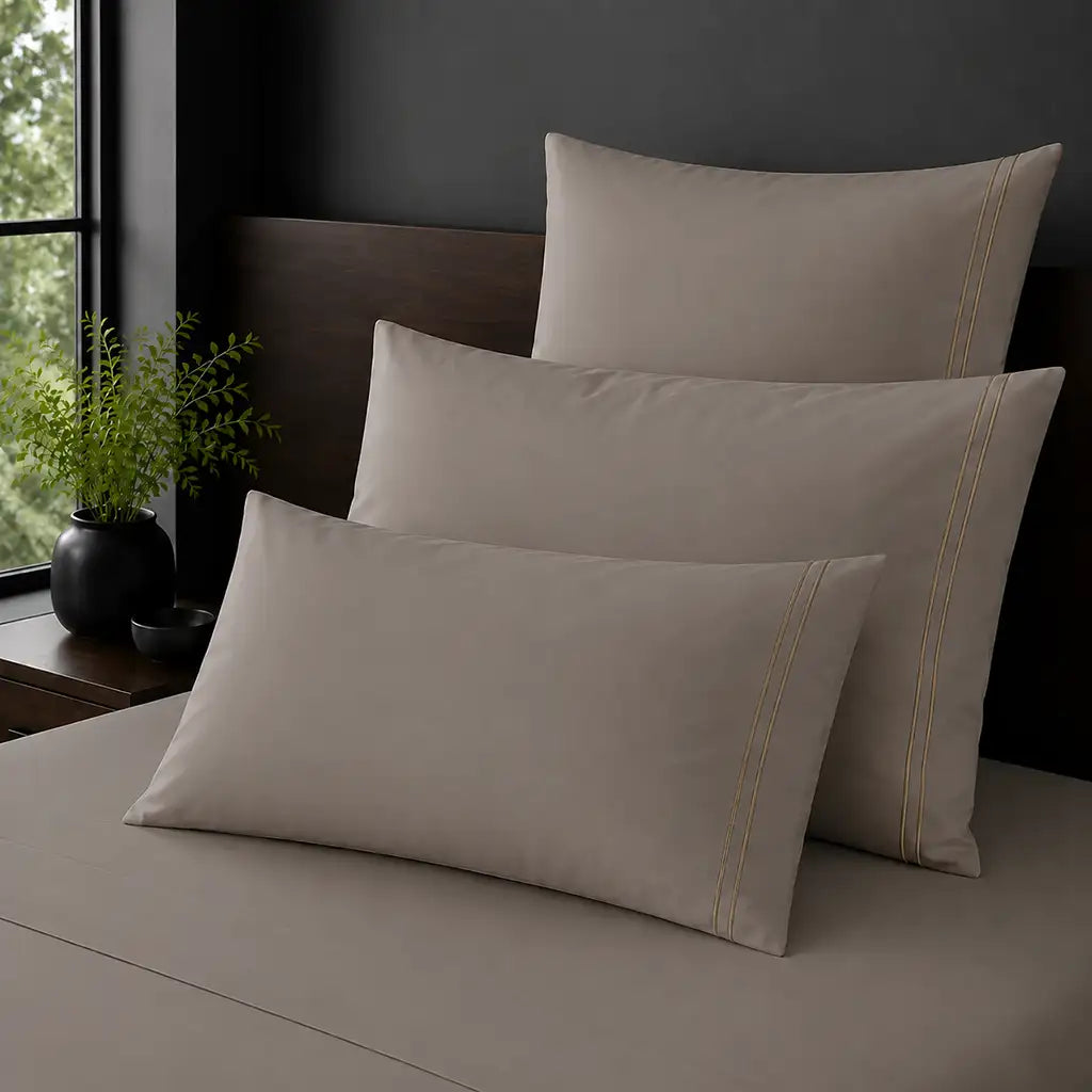 Stone Polycotton Percale 200TC Standard, King and Continental pillowcases on a bed with two row of stone satin stitch.